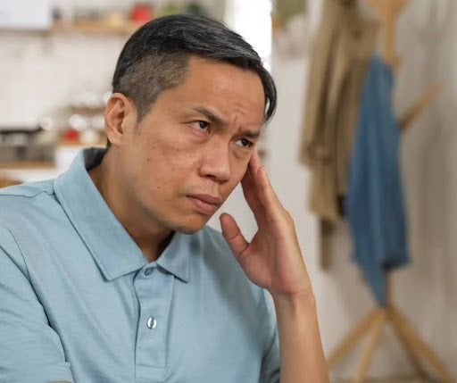 An older man looks upset as he touches his ear.