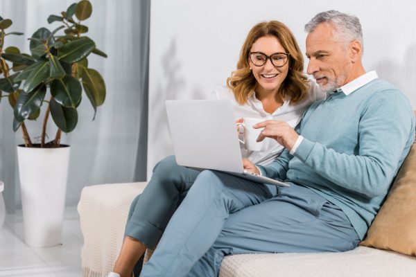 handsome mature man and pretty lady with laptop taking a hearing test online