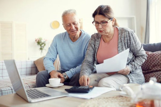 A mature couple working out the numbers for why are hearing aids so expensive