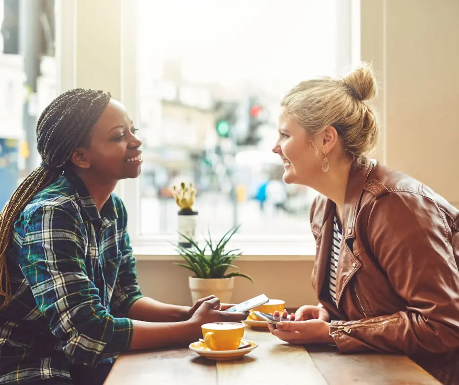 A man smiles at a woman as she speaks during their lunch.