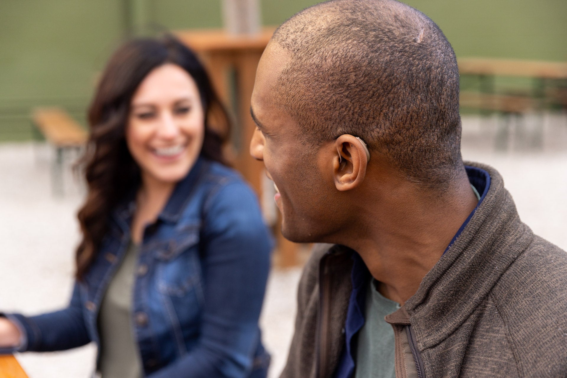 Two people sitting outdoors, one smiling, blurred background