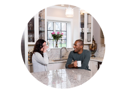 Two people sitting at a kitchen counter, enjoying coffee.