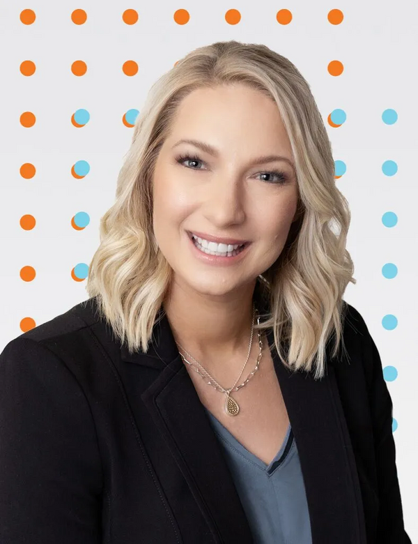 Woman with blonde hair and a black blazer against a polka dot background