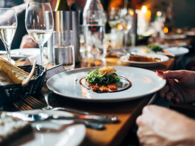 Dinner table with a plate of food, wine glasses, and cutlery in a restaurant setting.