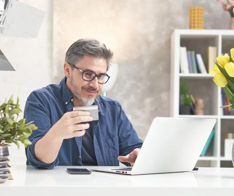 Man using a laptop and smartphone in a home office setting