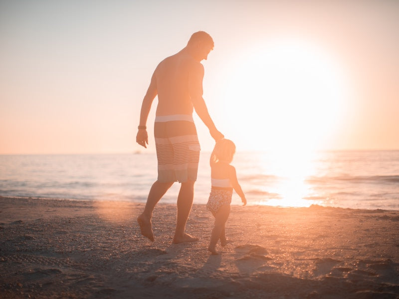 Man walking hand in hand with child on the beach 
