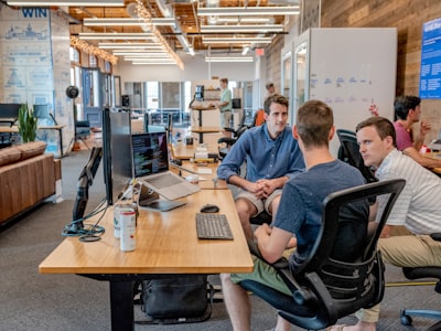 People working in a modern office with computers and casual attire.