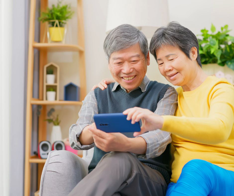 An older couple smiles as they look at a smartphone.
