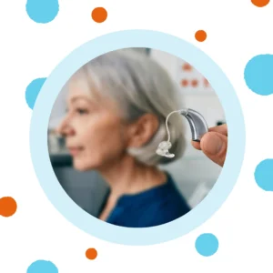 A woman holds a BTE hearing aid near her ear. 