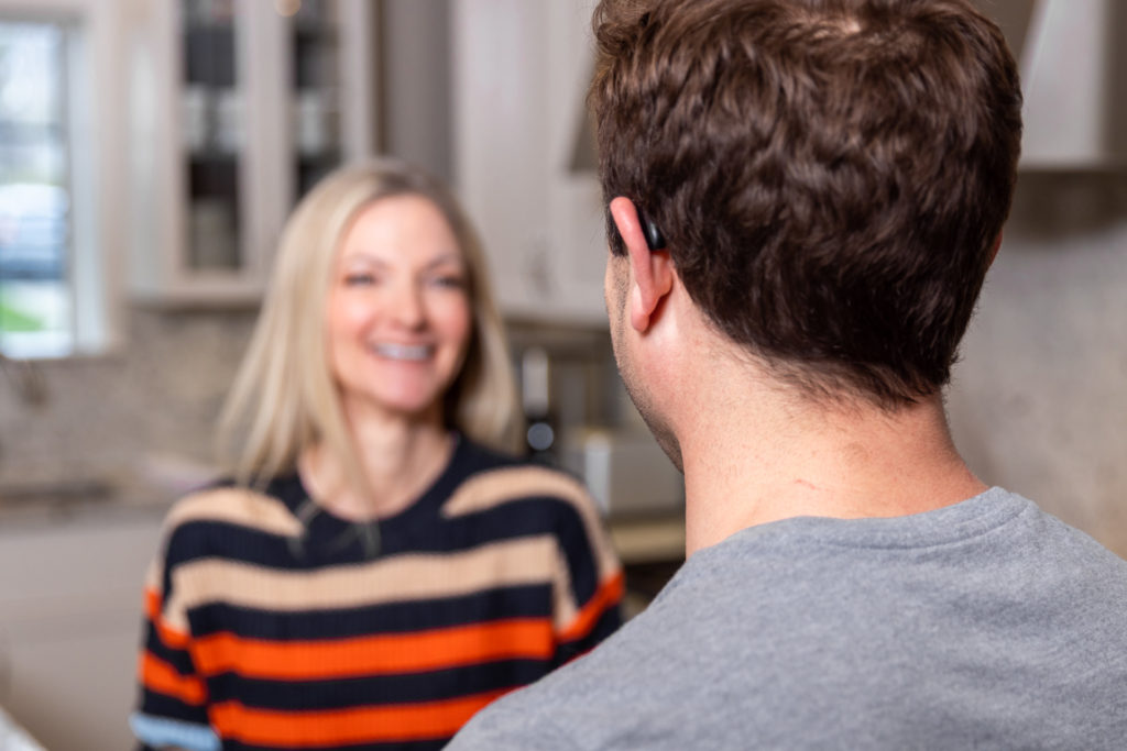 Back of man's head as he's talking to his wife in the kitchen showing his almost invisible hearing aids from Injoy