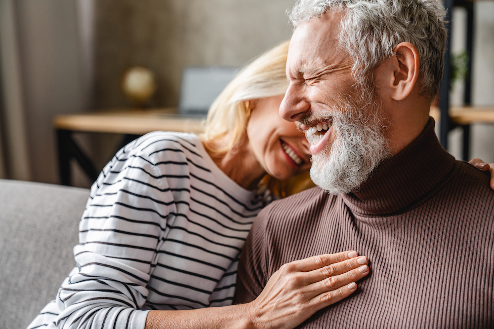 mature couple laughing together on couch because they know where do I get a hearing aid