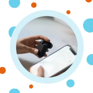 A hand holds a hearing aid next to a phone. 