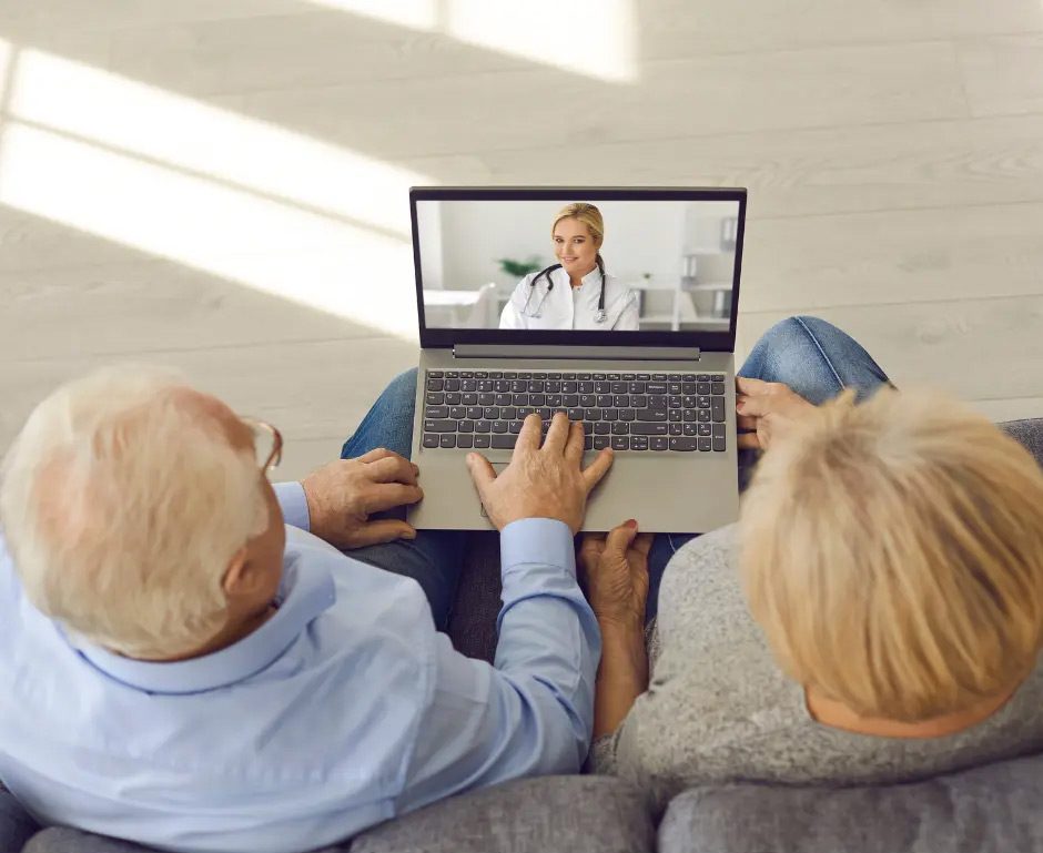 An older couple has a telehearing appointment on a laptop.