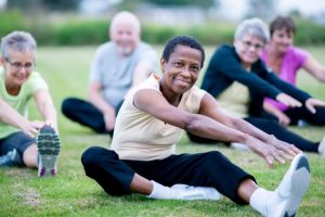 Older people do yoga outside.