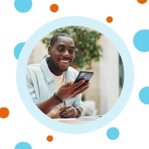 A man smiles at his phone. 