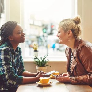 A man smiles at a woman as she speaks during their lunch.