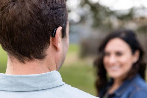 A man wearing a RIC hearing aid facing his wife.