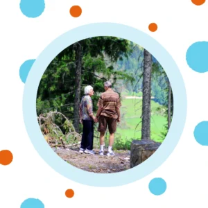 An older couple hikes in the woods. 