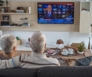 An older couple watching TV from their couch