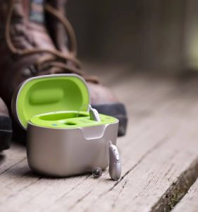 One rechargeable hearing aid rests next to its charger