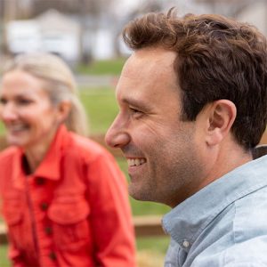 A couple smiles while chatting with friends.