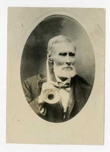 An old man using an ear horn, an early hearing aid.