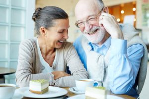 An older couple laughs over dessert. 