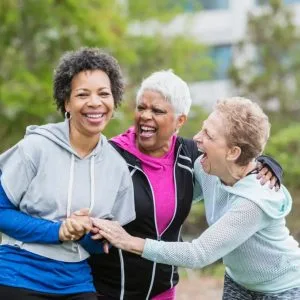 Older friends laugh while they exercise.