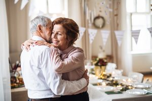 An older couple hugs in a room set up for a party.