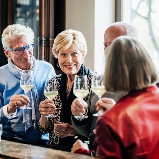 Older people toast and smile at a restaurant. 