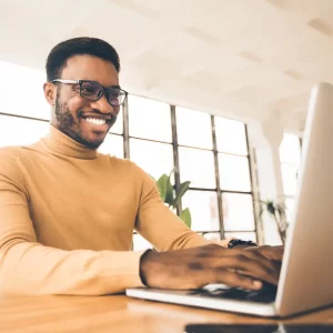 A man smiles at his laptop screen.