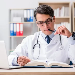 An audiologist refers to a book during a teleaudiology appointment. 