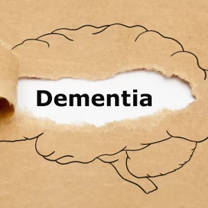 An outline of a brain with the word ‘dementia’ written in it sits on a beige background.
