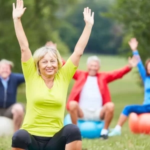 Older people doing yoga outside.