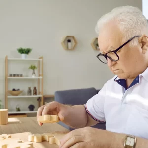 An older man completes a puzzle. 