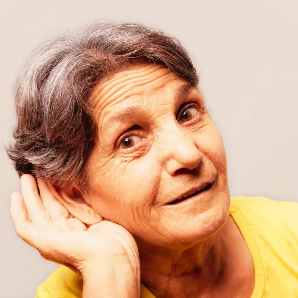 An older woman cups her ear and leans in to hear better.