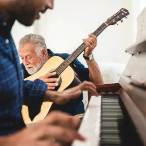 One man plays the piano, and another plays guitar happily. 