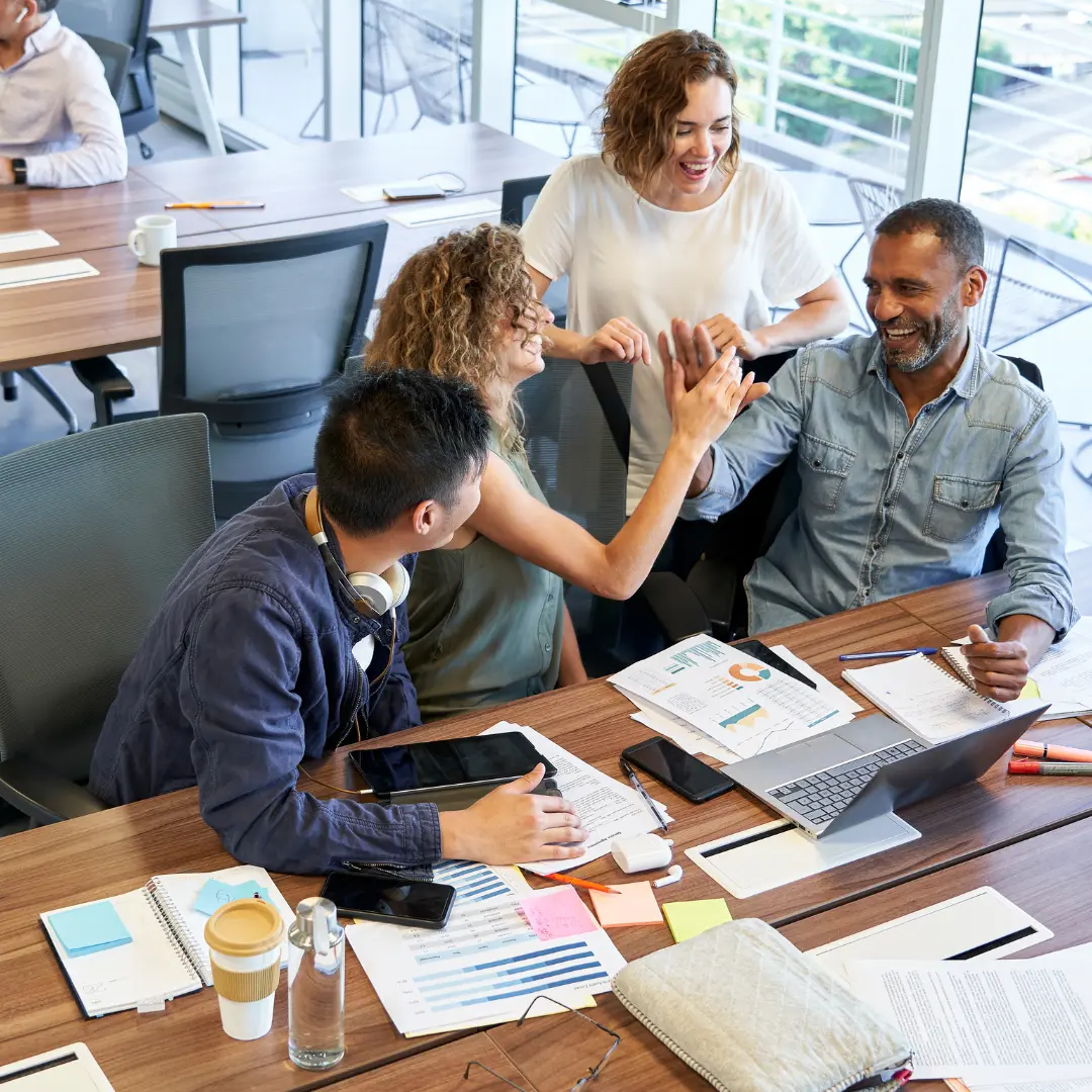 Coworkers chuckle and high-five at work.