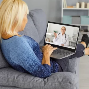 A woman consults with a hearing provider on her laptop. 