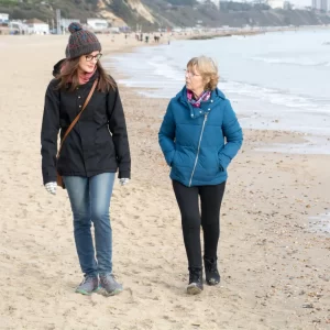 Two friends walk on the beach. 