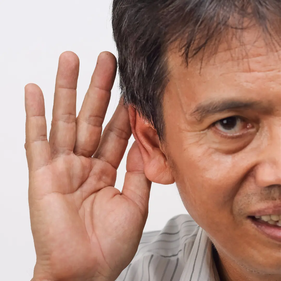 A man cups his hand around his ear to hear better.