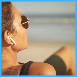 A woman on a beach wearing an AirPod.