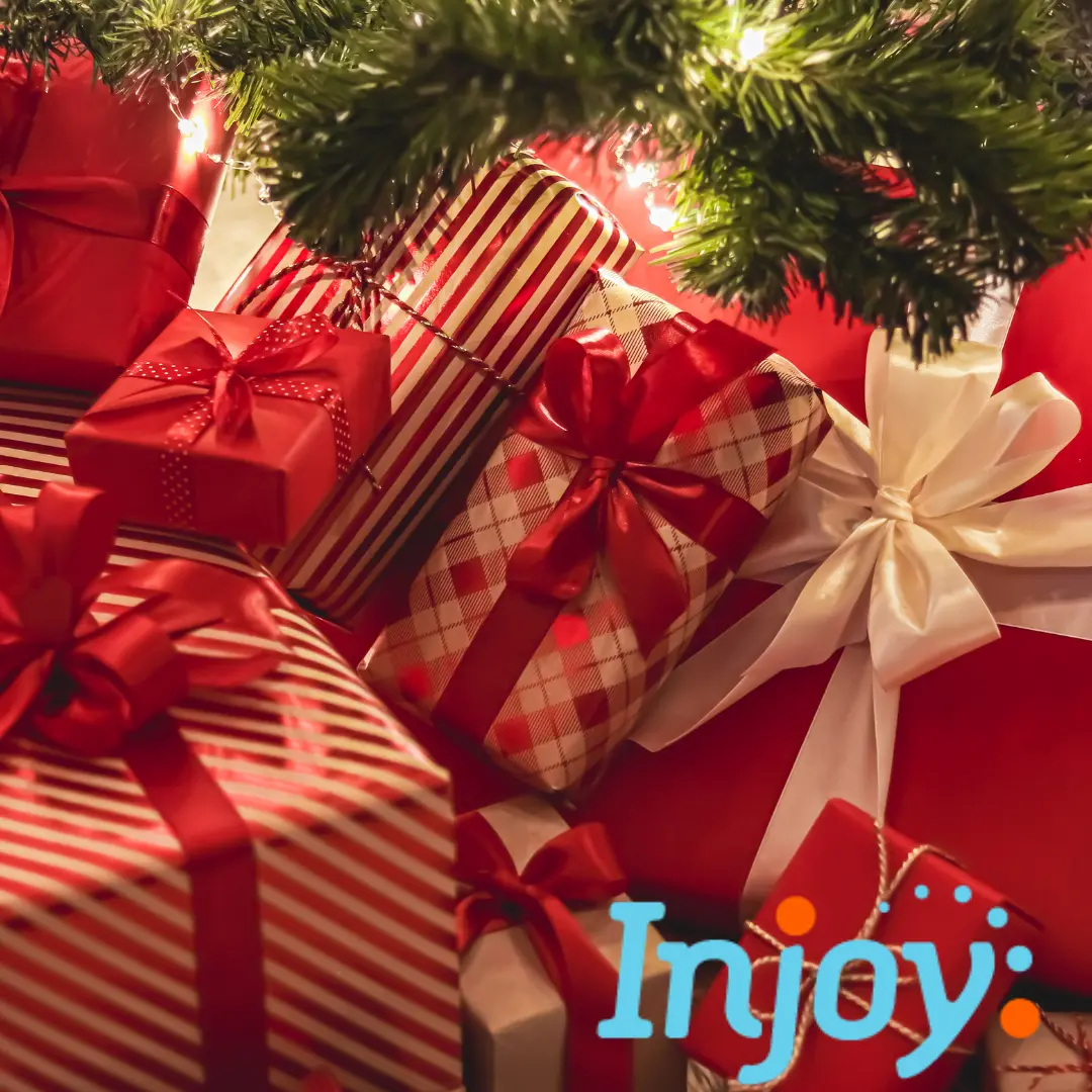 A pile of gifts sits under a Christmas tree.