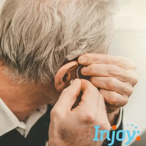 A man puts his hearing aid in. 