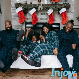 A family sits in front of their fireplace in holiday pajamas.