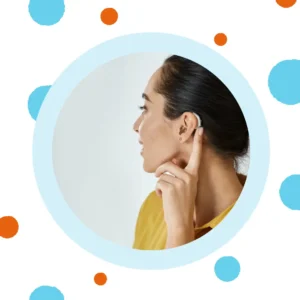A woman touches her hearing aid. 
