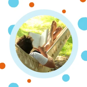 A woman reads a book on a hammock. 