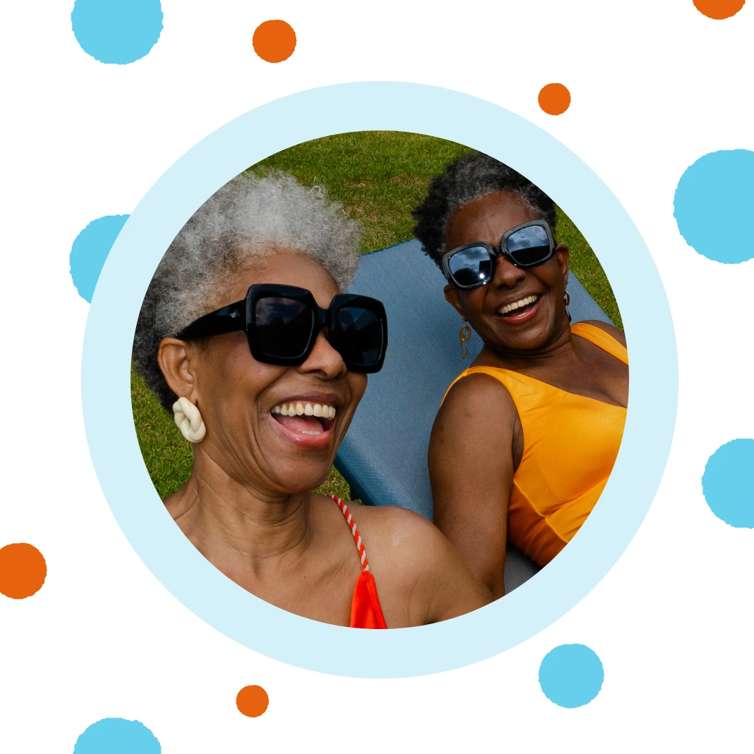 Two older woman laugh together by a pool.