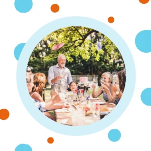 An extended family enjoys dinner at a table outside. 