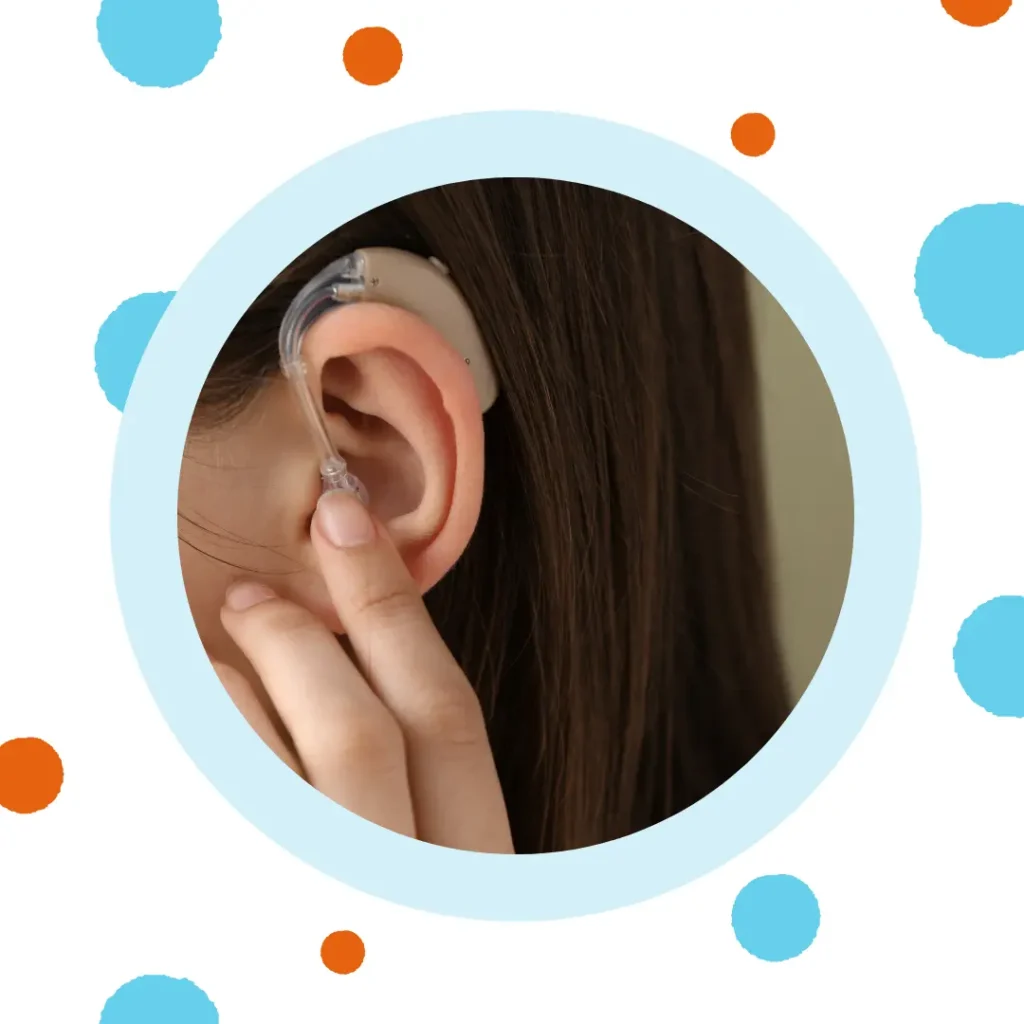 A hand places a BTE hearing aid on the ear.